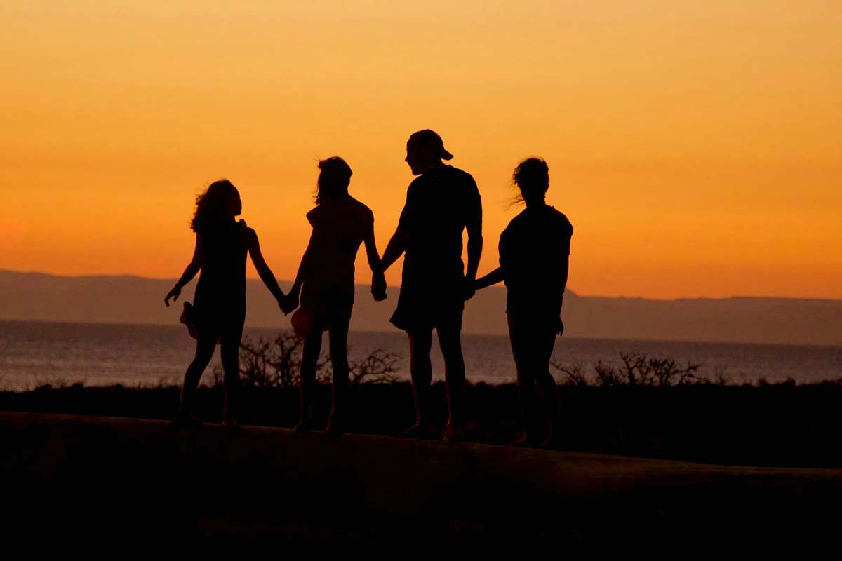 holding hands silhouette of man standing beside shore under brown sky during daytime silhouette